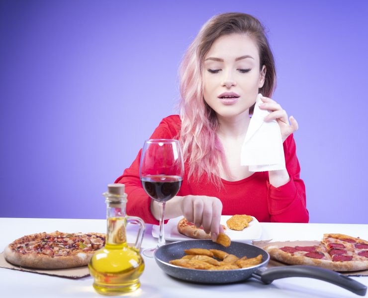 sweet girl with a napkin in one hand takes a wedge of fried potato