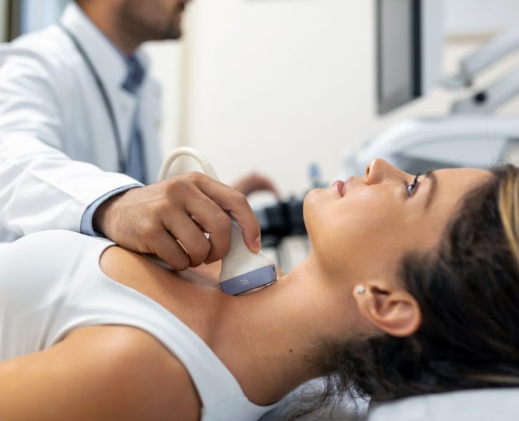 Close up shot of young woman getting her neck examined by doctor using ultrasound scanner at modern clinic